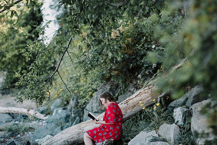 woman reading Bible along creek